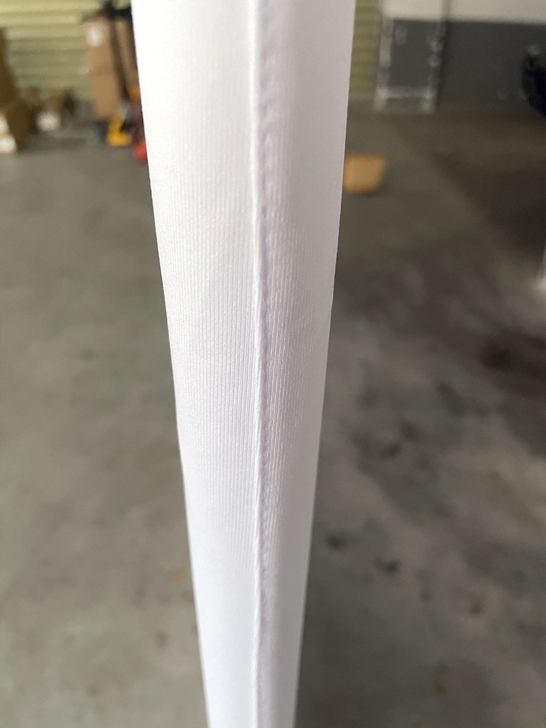 Peut inclure: Gros plan sur un tissu blanc avec une couture verticale. Le tissu pr&eacute;sente une texture subtilement c&ocirc;tel&eacute;e, et la couture est une fine ligne droite de couture. L'impression g&eacute;n&eacute;rale est propre et minimaliste.
