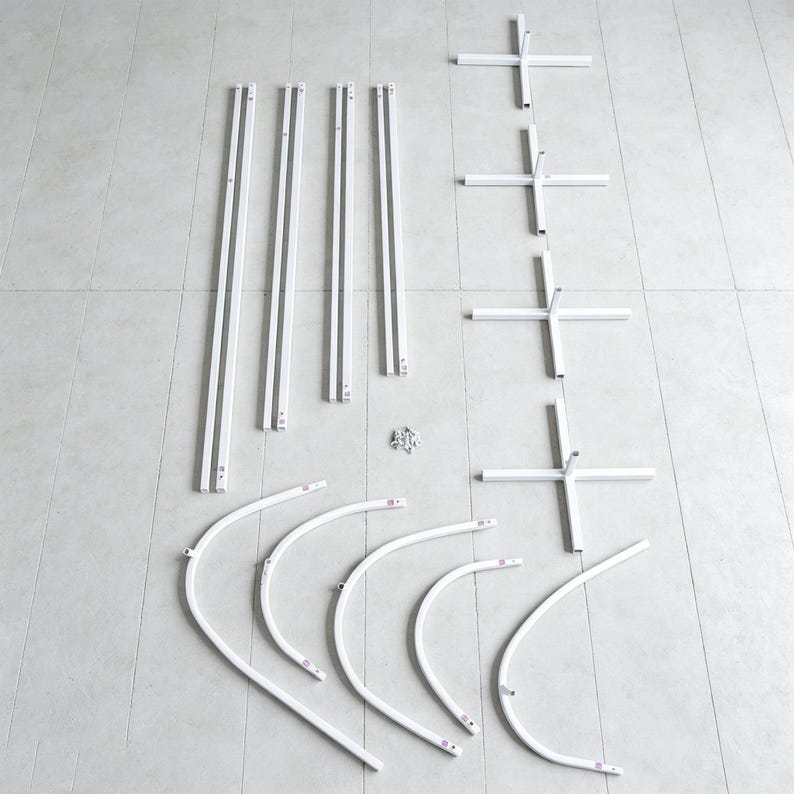 May include: A set of white metal components for an assembly kit, including four long straight poles, four cross-shaped base stands, five curved arch segments, and a small collection of metal screws and fasteners arranged on a flat surface.
