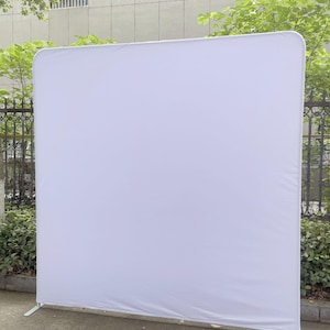 Peut inclure: Un grand &eacute;cran de fond blanc de forme rectangulaire avec des coins arrondis. L'&eacute;cran est soutenu par un cadre m&eacute;tallique blanc avec deux pieds pour la stabilit&eacute;. La toile de fond est en tissu lisse et infroissable.