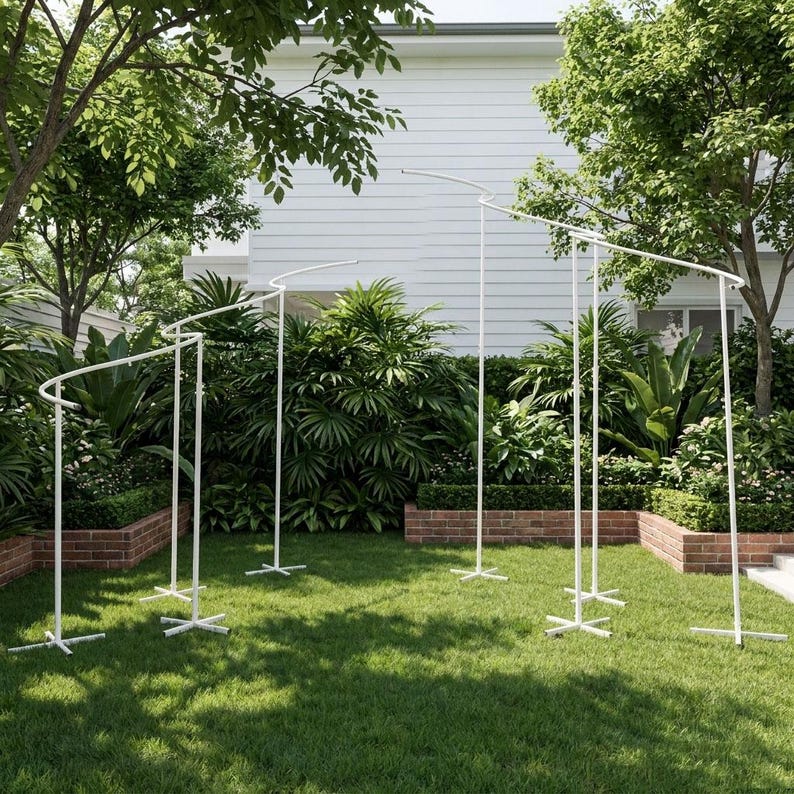 May include: A white metal backdrop stand featuring a series of interconnected vertical poles and curved horizontal bars. The structure is supported by multiple cross-shaped bases, creating a tiered, wave-like frame for event displays and decorations.
