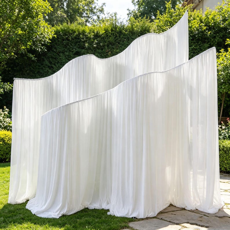 May include: A freestanding room divider featuring multiple layers of sheer white fabric draped over a curved frame. The fabric creates soft, vertical folds and undulating, wave-like edges that cascade downward, forming a semi-transparent partition.