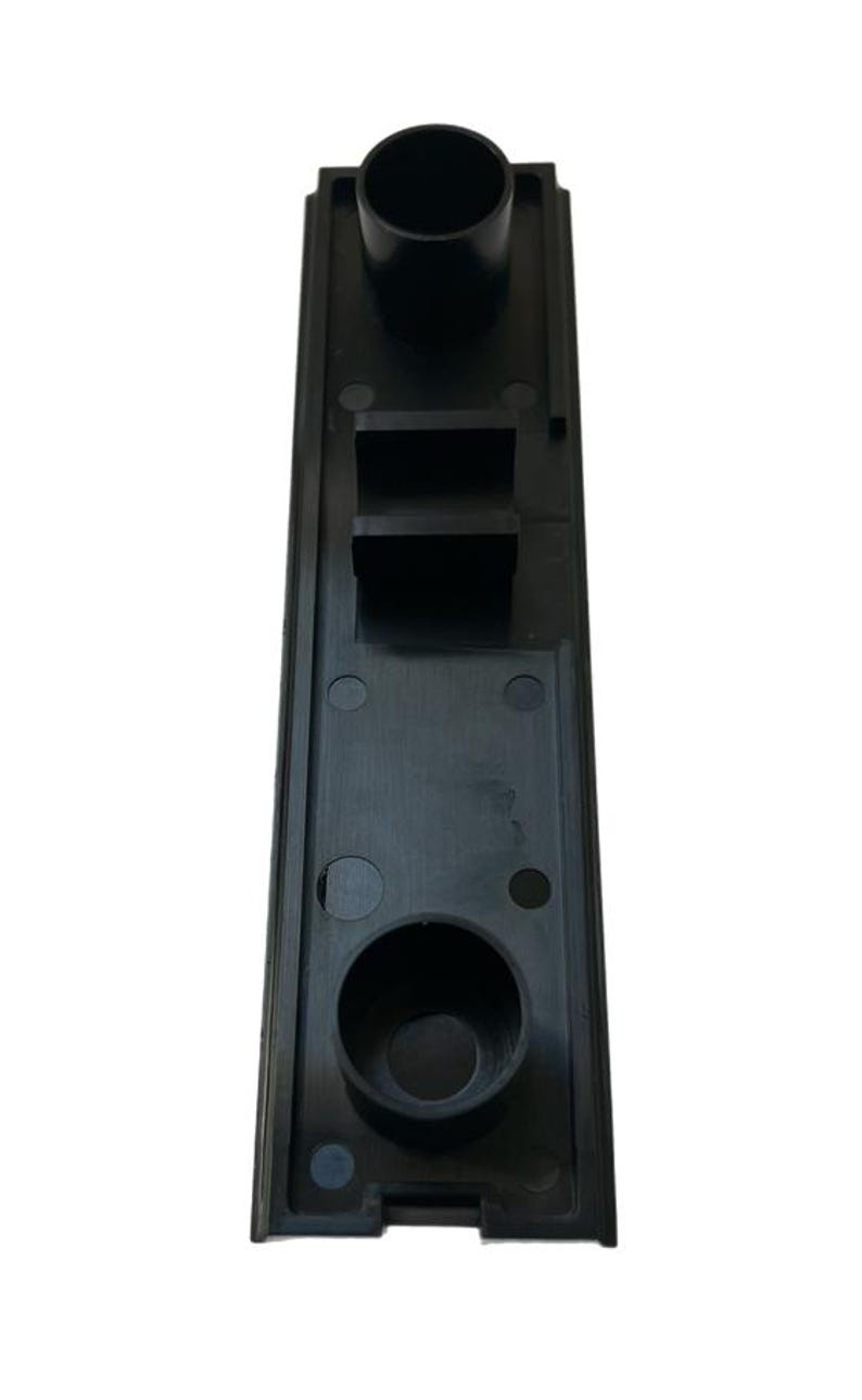 May include: Black plastic component with two round openings and a rectangular slot. The component has a textured surface and is designed for a specific purpose.