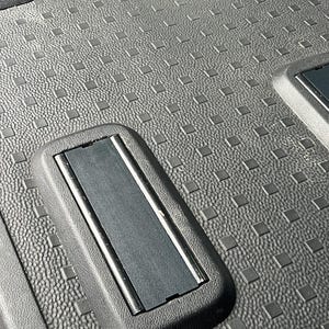 May include: Close-up of a black plastic cargo liner with a textured surface and a rectangular cutout with a black rubber strip.
