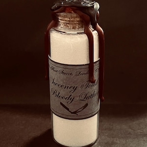 May include: A small glass bottle filled with white powder, sealed with a cork and dark brown wax. The label reads "Sweeney Todd Bloody Lather" with a razor illustration. The wax drips down the sides of the bottle.