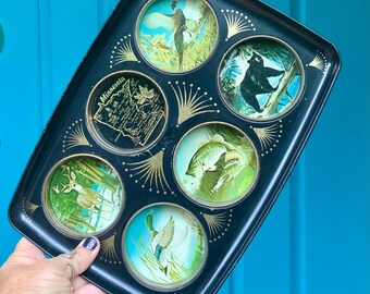 May include: A vintage black metal tray with six circular wildlife illustrations. The tray features images of a bird, bear, fish, deer, duck, and a map of Minnesota. Gold accents and a decorative border complete the design.