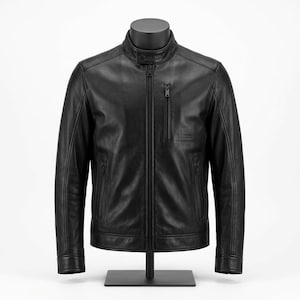 May include: A black leather jacket featuring a stand-up collar with a snap button closure, a full-length front zipper, and three zippered pockets. The jacket includes a small embossed logo on the chest and long sleeves with buttoned cuffs.