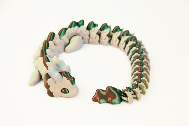 May include: A whimsical, articulated dragon figurine in shades of white, green, and brown. The dragon has a detailed, segmented body and a cute, expressive face. The toy is designed to be flexible and poseable.
