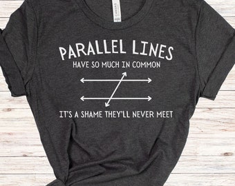May include: A dark gray t-shirt with a white graphic that says "Parallel Lines Have So Much In Common It's A Shame They'll Never Meet". The graphic also includes a diagram of two parallel lines with a diagonal line intersecting them.