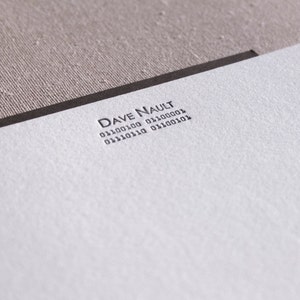 May include: A white card with black text that reads "DAVE NAULT 011001100 01100001 01110110 01100101".