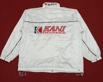 May include: White windbreaker jacket with blue trim and the logo "KANI ENDURANCE" in red and blue lettering.