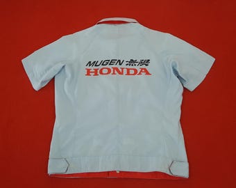 May include: Light blue short-sleeved work shirt with red and black "MUGEN 無限 HONDA" logo on the back. The shirt has a red collar and cuffs, and two buttons on each sleeve. The shirt is made of a lightweight material.