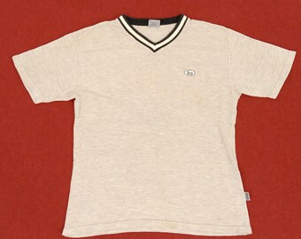 May include: A gray and white striped t-shirt with a black and white v-neck collar. The shirt has a small logo on the front that says "b".
