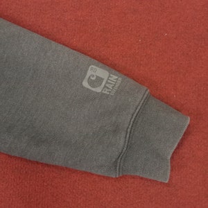 May include: A dark gray sweatshirt with a Carhartt logo and the text "Rain Defender" on the sleeve.