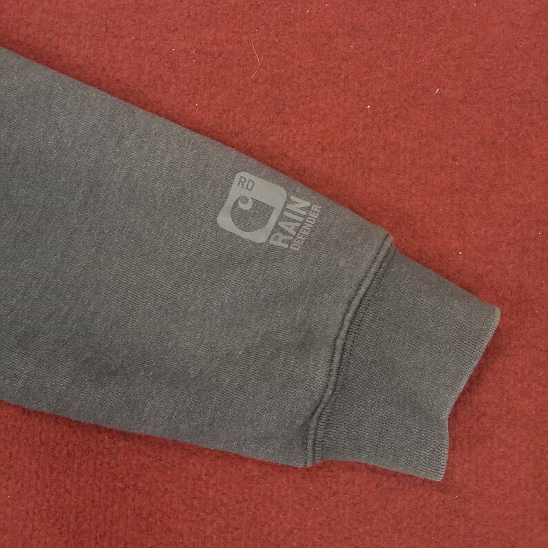 May include: A dark gray sweatshirt with a Carhartt logo and the text "Rain Defender" on the sleeve.