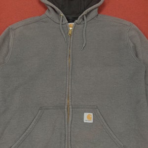 May include: A gray hooded sweatshirt with a zipper closure and a Carhartt logo patch on the front.