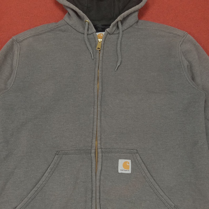May include: A gray hooded sweatshirt with a zipper closure and a Carhartt logo patch on the front.