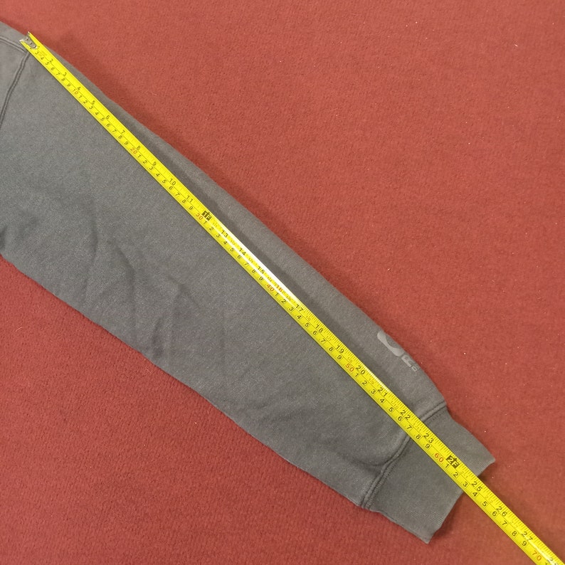 May include: A gray sweatshirt sleeve with a yellow measuring tape showing a length of 23 inches.