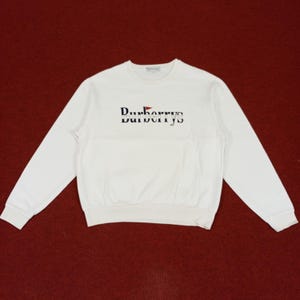 May include: White long-sleeve sweatshirt with a navy blue embroidered logo that says "Burberrys" with a red and blue flag design.