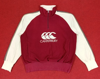 Puede incluir: Una sudadera de manga larga roja y blanca con cremallera y un logotipo de Canterbury en la parte delantera.