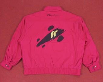 May include: A magenta jacket with long sleeves and a buttoned cuff. The back of the jacket features a black and yellow graphic with the text "F1 GP". The jacket has a collared neckline and a gathered waist.