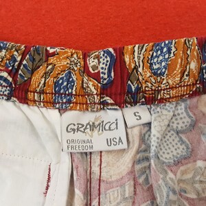 May include: Close-up of patterned shorts with a red waistband and a white interior. The shorts have a colourful print with blue, orange, and brown designs. The tag reads "GRAMICCI ORIGINAL FREEDOM USA" and the size is "S".