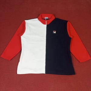 May include: A white and navy blue zip-up jacket with red sleeves. The jacket has a Fila logo on the front.