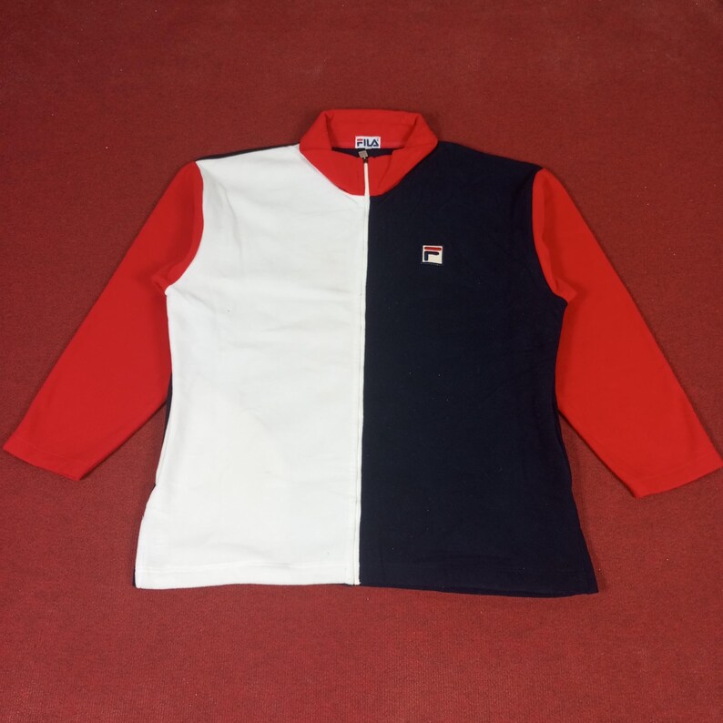 May include: A white and navy blue zip-up jacket with red sleeves. The jacket has a Fila logo on the front.