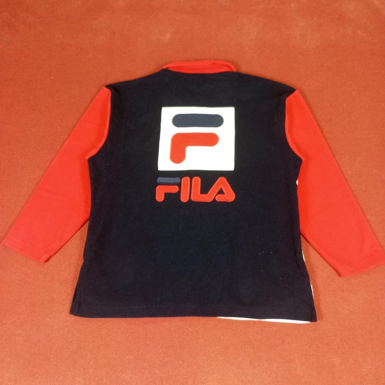 May include: A black long-sleeve shirt with red sleeves and a white and red Fila logo on the back.