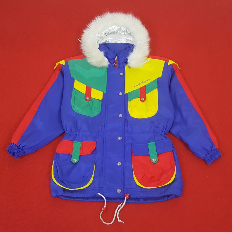 Puede incluir: Una colorida chaqueta de invierno con capucha forrada de piel sint&eacute;tica blanca. La chaqueta tiene una base azul con detalles rojos, verdes y amarillos en los bolsillos y los hombros. Tiene cintura ajustable y la palabra "courreges" est&aacute; impresa.