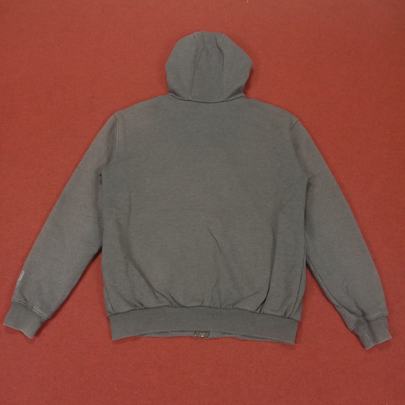 May include: A dark gray hooded sweatshirt with a zipper closure. The sweatshirt has a relaxed fit and long sleeves.