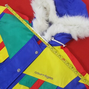Puede incluir: Una colorida chaqueta Courr&egrave;ges vintage con una capucha ribeteada con piel sint&eacute;tica blanca. La chaqueta presenta un vibrante dise&ntilde;o de patchwork en azul, verde, amarillo y rojo. La chaqueta tiene botones plateados y el logo de Courr&egrave;ges.