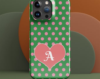 May include: Green phone case with pink polka dots and a pink heart shape. The heart contains the letter "A" in white. The phone case has a glossy finish and is designed for a smartphone.