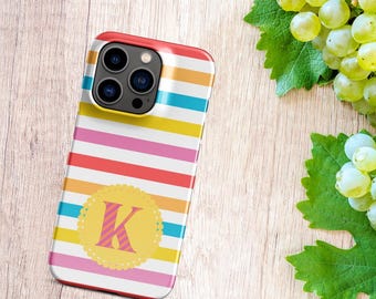 May include: A colorful striped phone case with a yellow circle and the letter "K" in pink. The case is designed for an iPhone with a camera bump.