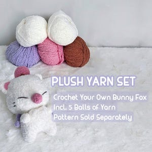 May include: A plush yarn set with a white bunny fox and five balls of yarn in white, pink, brown, and purple. The text reads "PLUSH YARN SET" and "Crochet Your Own Bunny Fox".
