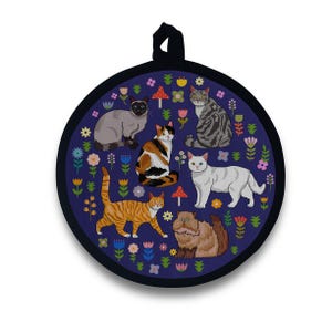 May include: Round navy blue pot holder featuring a whimsical design of various cat breeds surrounded by colorful flowers and mushrooms. The pot holder has a black loop for hanging and is approximately 8 inches in diameter.