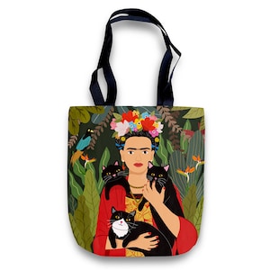 May include: A tote bag featuring a colorful illustration of Frida Kahlo with three black cats. The background is a green jungle scene with flowers and birds.