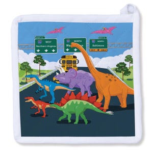 May include: A white potholder with a colorful illustration of dinosaurs on a highway. The image includes a school bus, road signs, and pterodactyls. The dinosaurs are in various colors, including orange, blue, green, and purple.