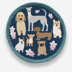 Peut inclure: Un dessous de plat rond en tissu bleu avec une bordure blanche présente un motif de différentes races de chiens, dont un corgi, un carlin, un teckel, un chihuahua, un lévrier, un bouledogue français et un caniche. Les chiens sont entourés de fleurs de cerisier roses.