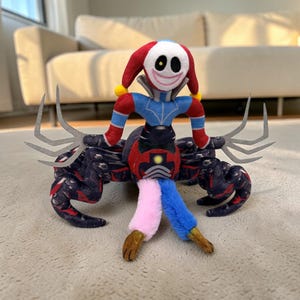 Puede incluir: Un peluche con una figura de payaso con una cara sonriente, ropa roja y azul y un cuerpo con múltiples patas. El juguete tiene un sombrero rojo y blanco, y el cuerpo es principalmente negro con un diseño estampado. Las piernas son rosas, azules y marrones.