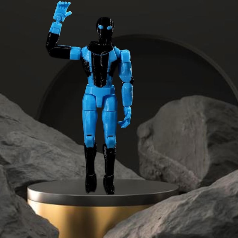 Op de afbeelding: Een blauw en zwart beweegbaar actiefiguur van een humano&iuml;de robot, met &eacute;&eacute;n arm omhoog. Het figuur staat op een goudkleurig platform, tegen een donkere achtergrond met rotsformaties.