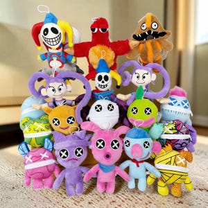 Puede incluir: Una colección de peluches coloridos con varios diseños. Los juguetes presentan diferentes formas, colores y expresiones faciales, incluyendo un bufón, una criatura roja con gafas de sol y una figura con forma de hongo. Cada juguete tiene un lazo para colgar.
