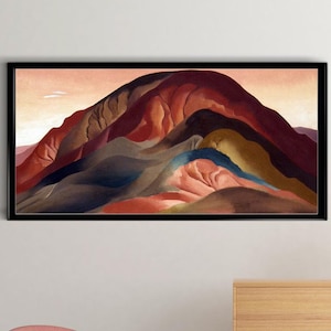 May include: A framed abstract painting of a landscape with a mountain range in shades of red, brown, green, and blue. The painting is hanging on a white wall above a wooden dresser with a vase of dried flowers.