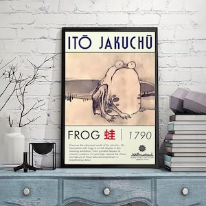 May include: Framed art print featuring a whimsical illustration of a frog. The artwork includes the text "ITO JAKUCHU" at the top and "FROG 蛙 | 1790" at the bottom. The print is displayed on a blue cabinet.