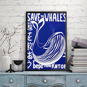 Puede incluir: Un póster enmarcado con un fondo azul y una ilustración de ballena blanca. El texto "SAVE THE WHALES" está en la parte superior, con texto japonés y cirílico debajo. El póster se exhibe en un mueble azul.