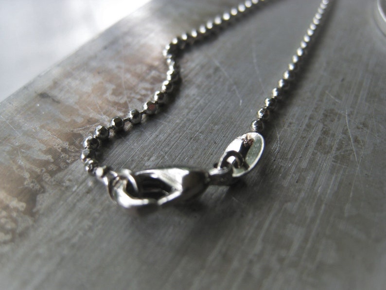 Puede incluir: Un collar de cadena de plata con un cierre de plata. La cadena est&aacute; hecha de peque&ntilde;as cuentas redondas.