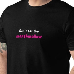 Op de afbeelding: Zwart T-shirt met witte tekst die "Eet niet de marshmallow" zegt in roze.