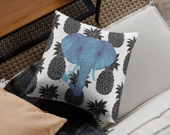 Peut inclure: Un coussin blanc avec un imprimé d'éléphant bleu et d'ananas noirs. L'éléphant est au centre du coussin et est entouré d'ananas.