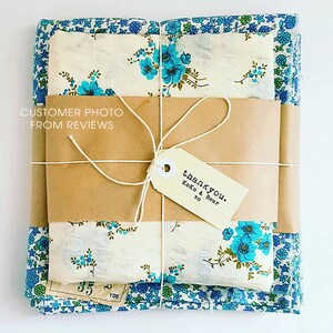 Peut inclure: Un paquet de tissu envelopp&eacute; dans du papier brun et attach&eacute; avec de la ficelle. Le tissu pr&eacute;sente des motifs floraux bleus et cr&egrave;me. Une &eacute;tiquette indique "thank you. Koko & Bear xo". Le texte "CUSTOMER PHOTO FROM REVIEWS" est visible.