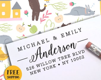 Puede incluir: Una tarjeta blanca con los nombres "MICHAEL & EMILY Anderson" impresos en negro. Debajo del nombre está la dirección "526 WILLOW TREE BLVD NEW YORK NY 10002". Un lápiz descansa sobre la tarjeta. El fondo presenta un patrón caprichoso con animales y casas de dibujos animados.