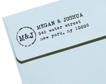 May include: A light blue envelope with black text. The text reads "MEGAN & JOSHUA" and their address. A circular stamp with "M&J" is on the left. The font is a typewriter style.